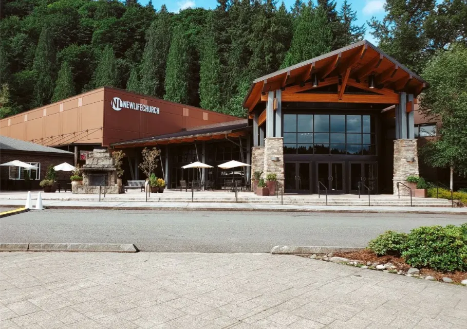 Modern church building with wooden roof and stone accents surrounded by trees