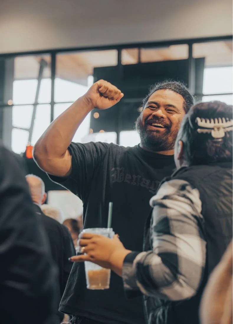 Excited man raising fist and laughing while holding drink