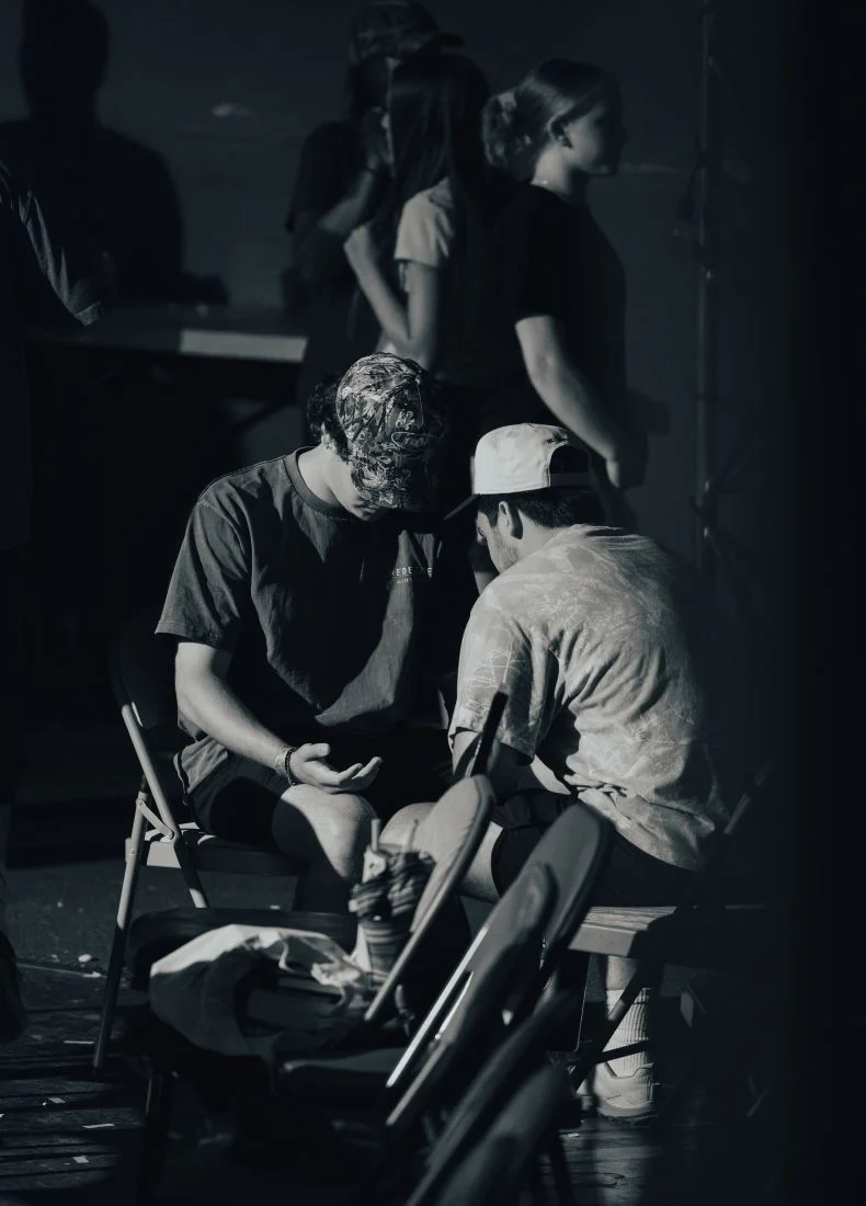 Two people sitting on chairs in dimly lit black and white scene