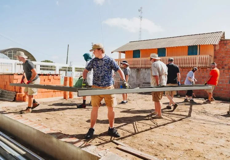 Construction workers carrying long metal beam on building site