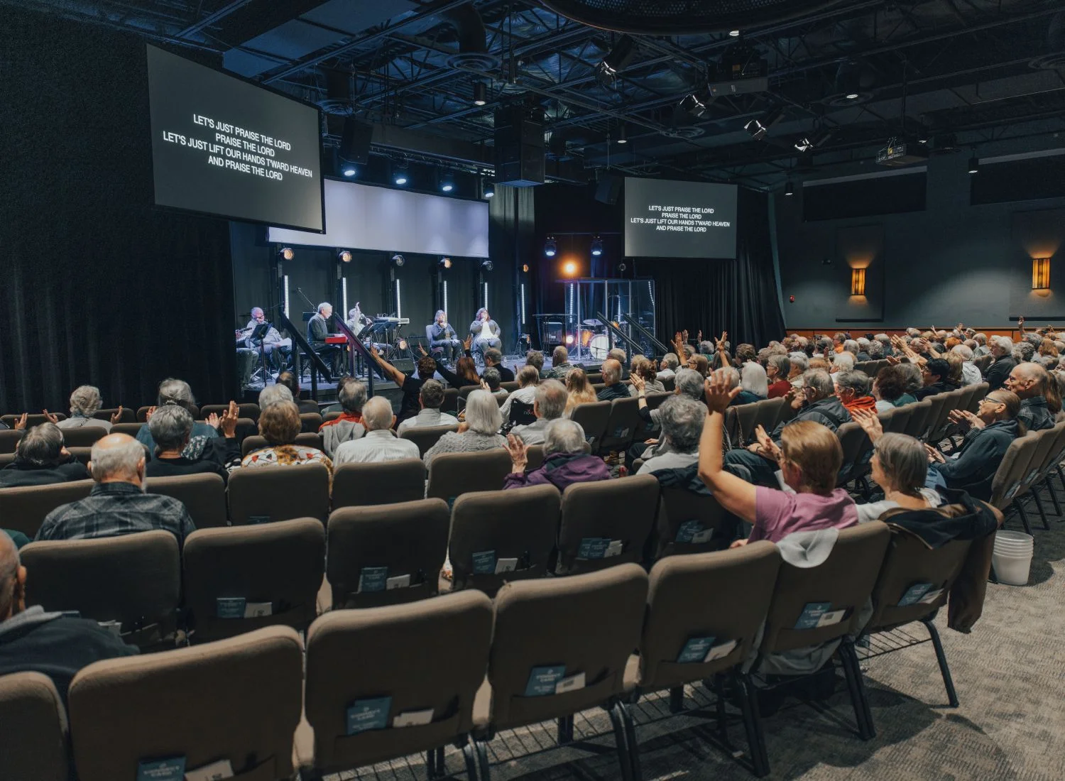 Church congregation worships during service with raised hands and lyrics