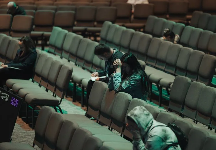 Audience members sit alone in empty auditorium during lecture or presentation
