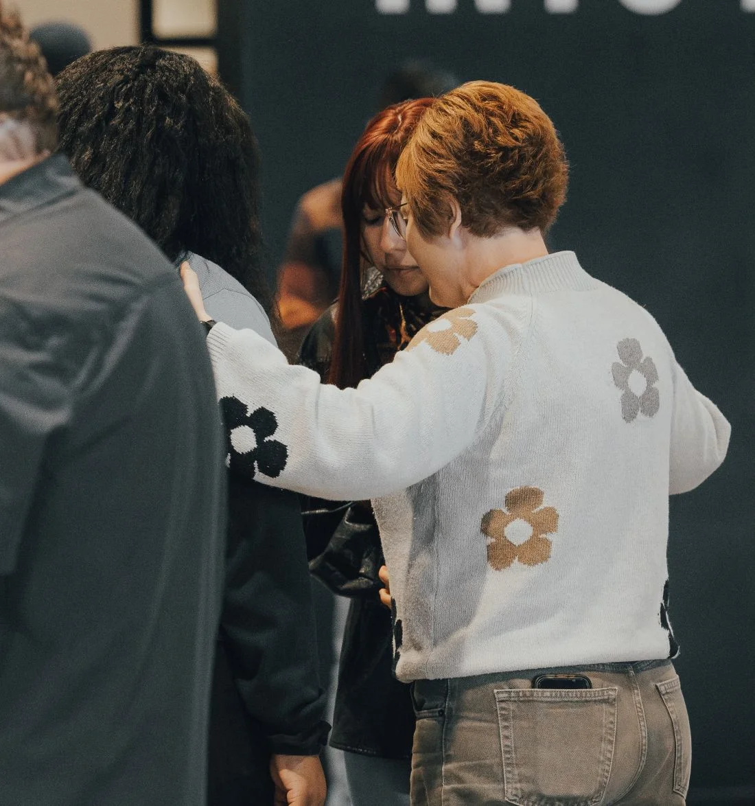 Two people hugging, wearing white sweater with flower patterns
