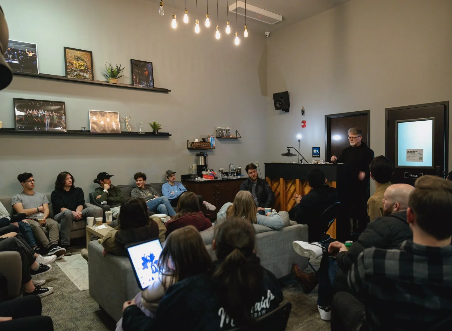Lecture or workshop with audience seated in modern, cozy room with hanging lights