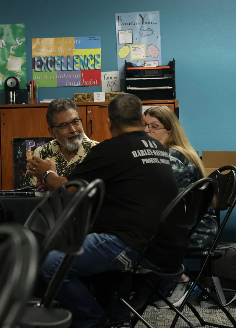 Educators discuss in classroom with motivational posters about excellence