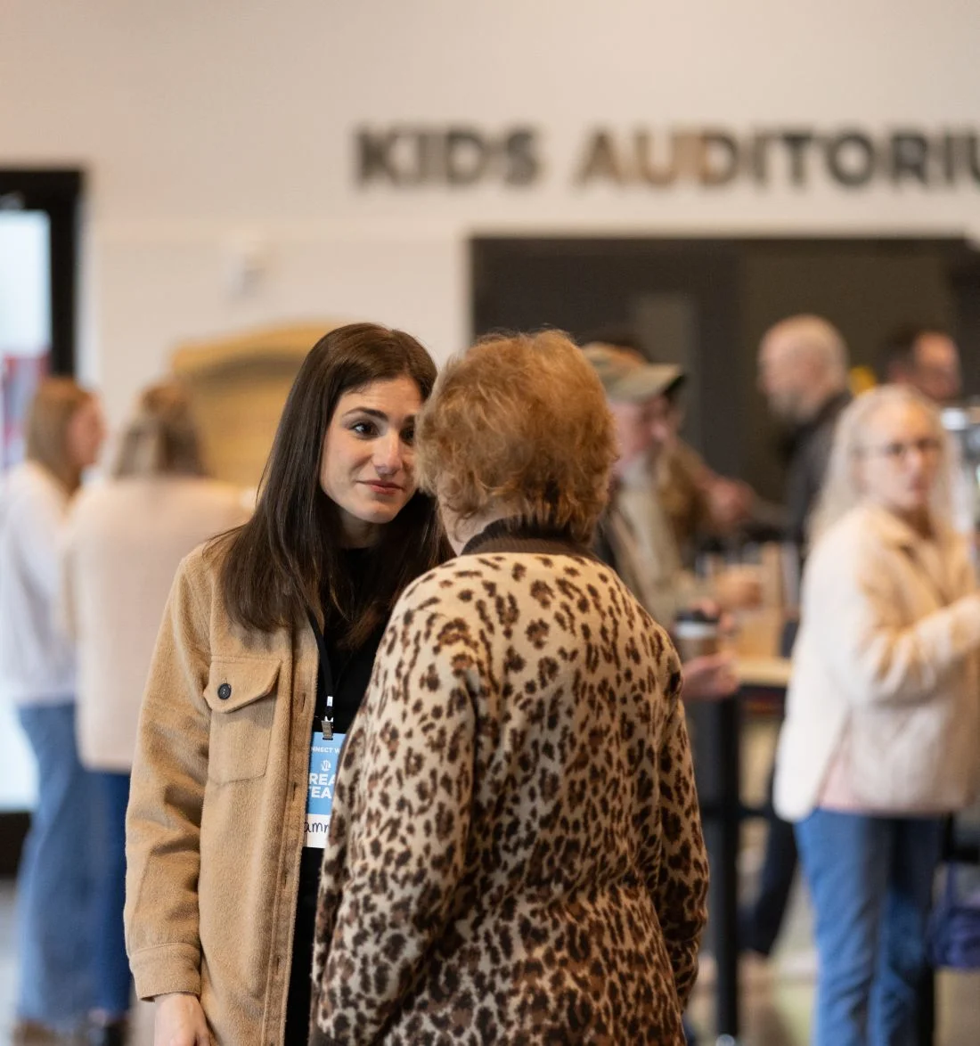 Two people talking near Kids Auditorium entrance with blurry background