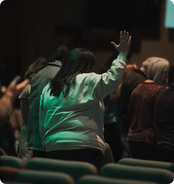 Person raising hand during a conference or presentation in dimly lit room