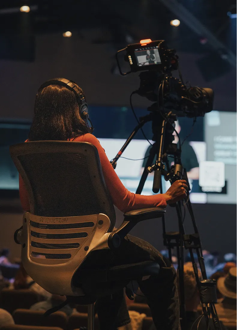 Videographer in red top operating camera at production event