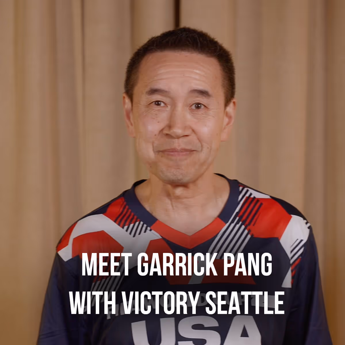 Smiling man wearing a colorful USA sports jersey standing in front of a beige curtain with text Meet Garrick Pang with Victory Seattle.