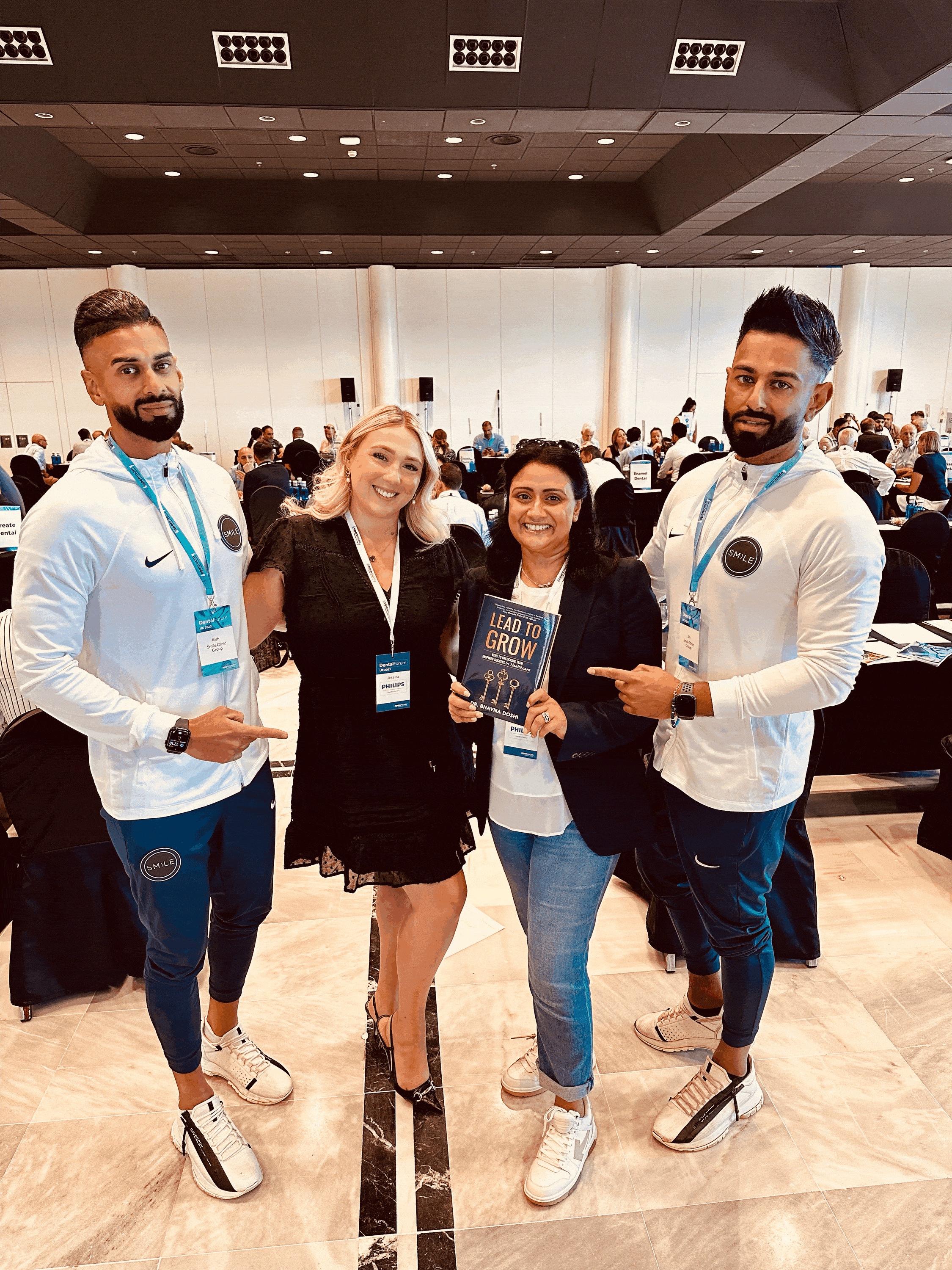 Four people at a Dental Forum event, one holding the book 'Lead to Grow'