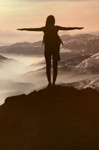 Lady expressing herself at the edge of a mountain