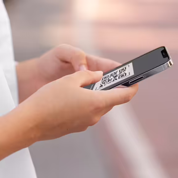 Person holding a smartphone displaying a QR code on the screen.