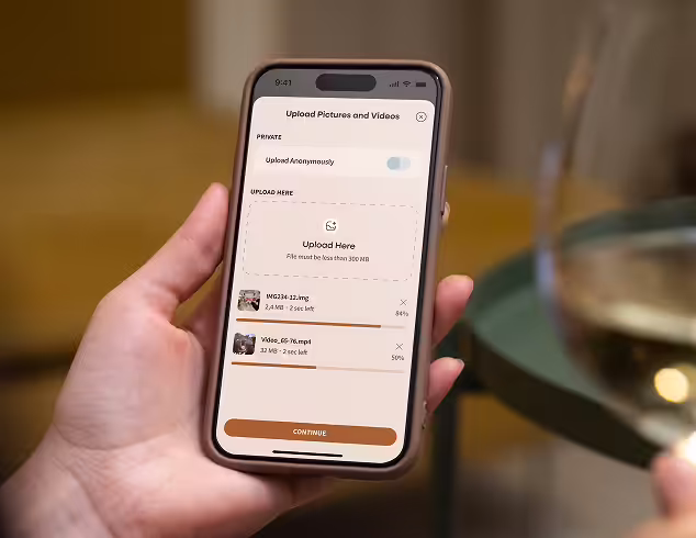 Hand holding a smartphone displaying a file upload screen with two files uploading and a 'Continue' button.