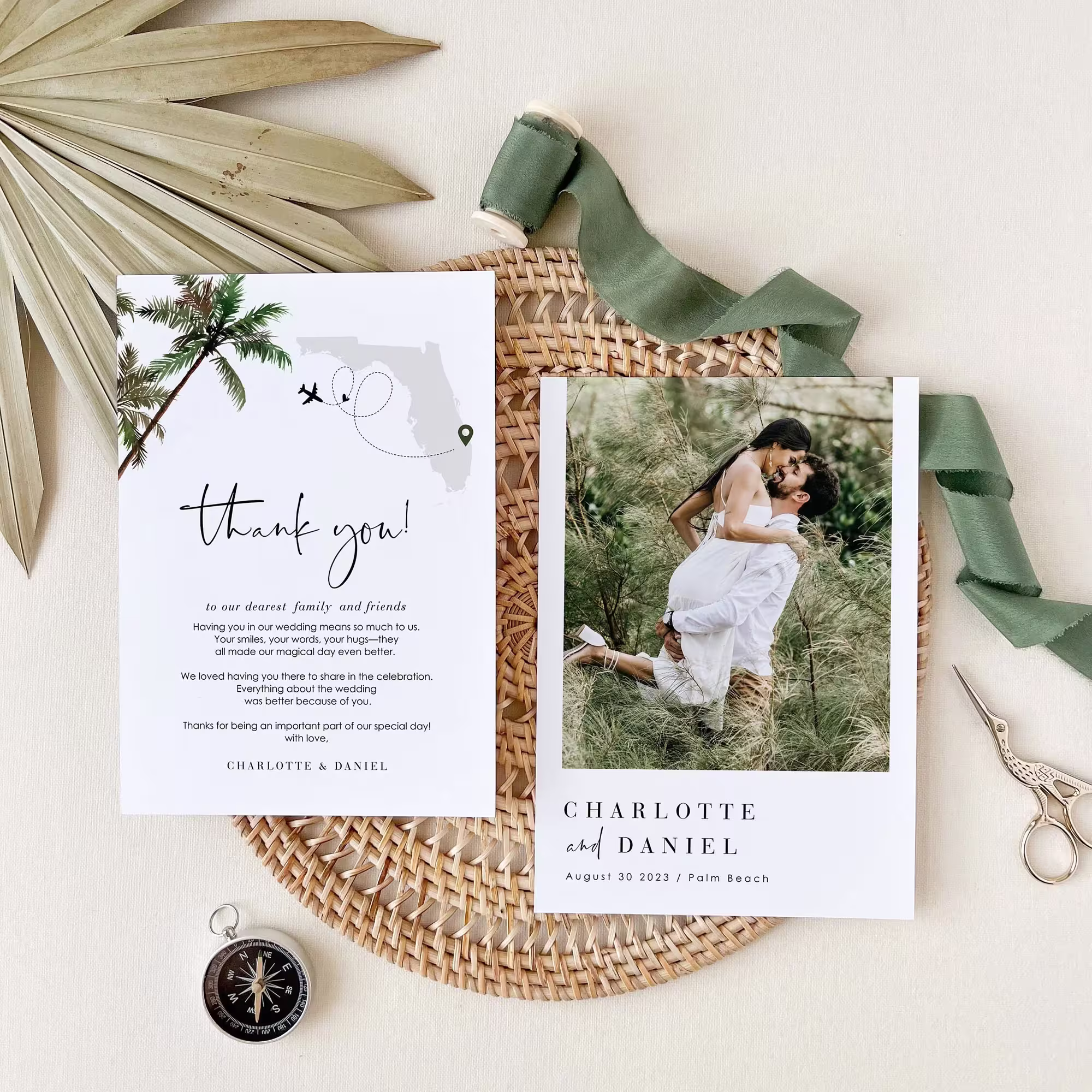 Wedding thank you cards with a photo of a couple embracing in a field, a map of Florida, and heartfelt message, arranged on a woven mat with green ribbon, palm leaf, scissors, and compass.