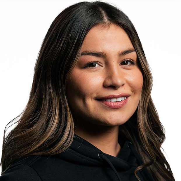 Smiling woman with long dark hair wearing a black hoodie against a white background.