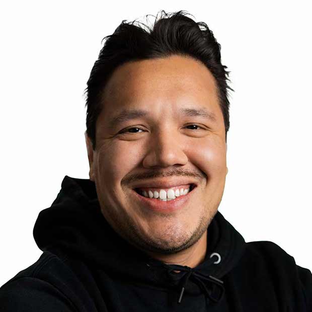 Smiling man with short dark hair wearing a black hoodie against a white background.