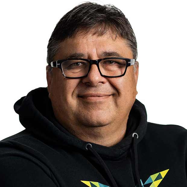 Middle-aged man with short dark hair and black glasses smiling, wearing a black hoodie with a colorful geometric design.