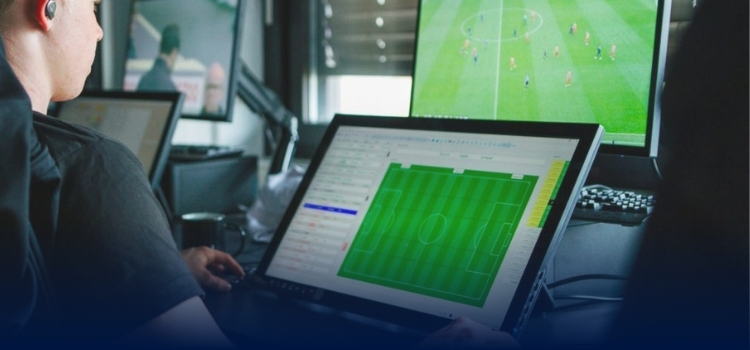A video analyst logging information from a soccer game on a laptop.