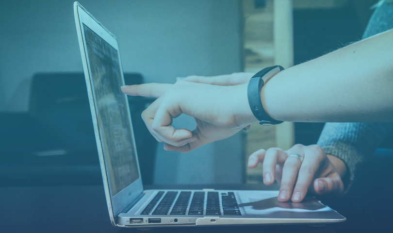 Two people pointing at a laptop screen as they work through a problem together