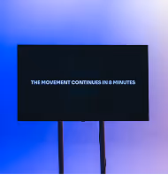 Screen with white text saying 'THE MOVEMENT CONTINUES IN 8 MINUTES' on a blue gradient background.