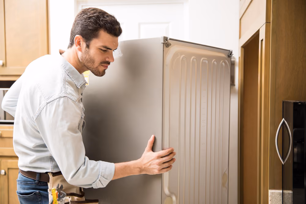 Technician inspecting back of Samsung refrigerator to diagnose loud humming noise issue