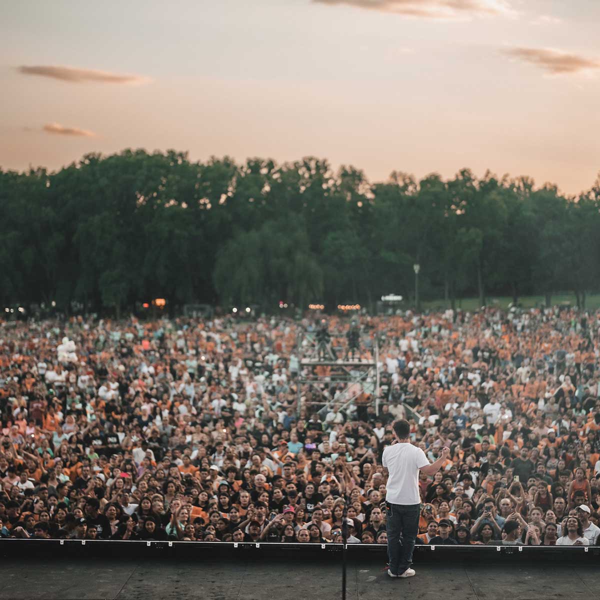 A man standing on stage speaking to a large crowd of people