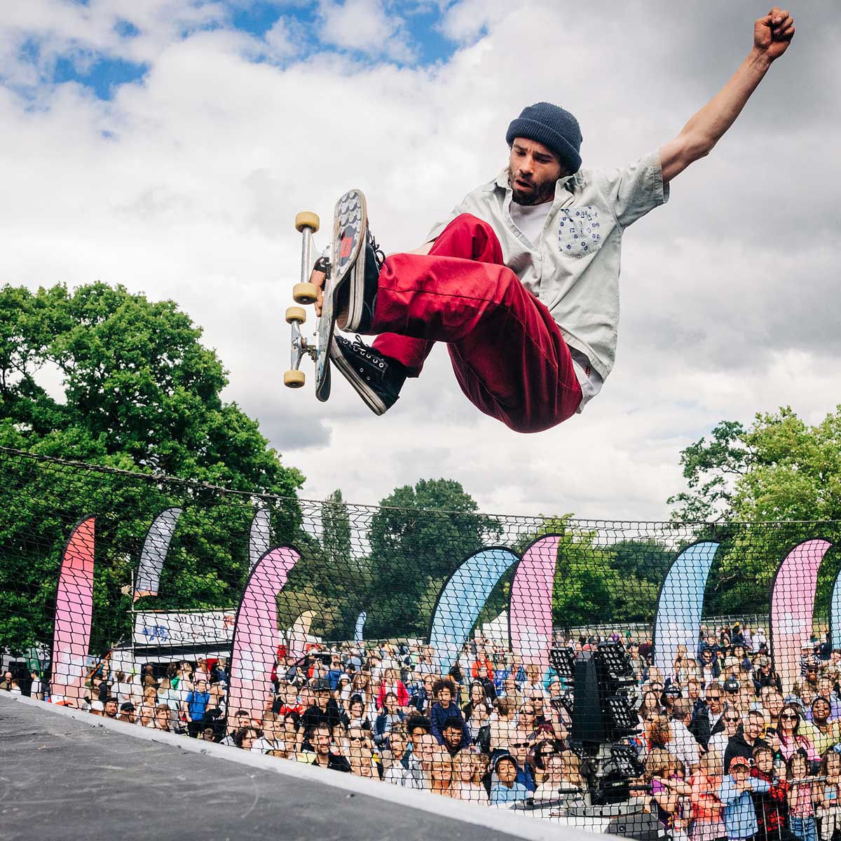 A skateboarder preforming a trick in midair with a crowd of people watching