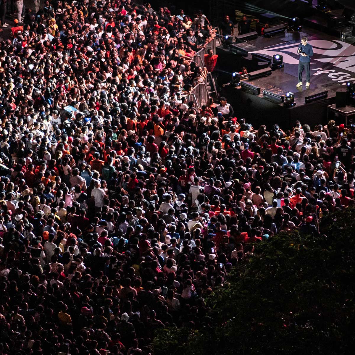 An aerial view of a large event with a man on stage speaking to the crowd
