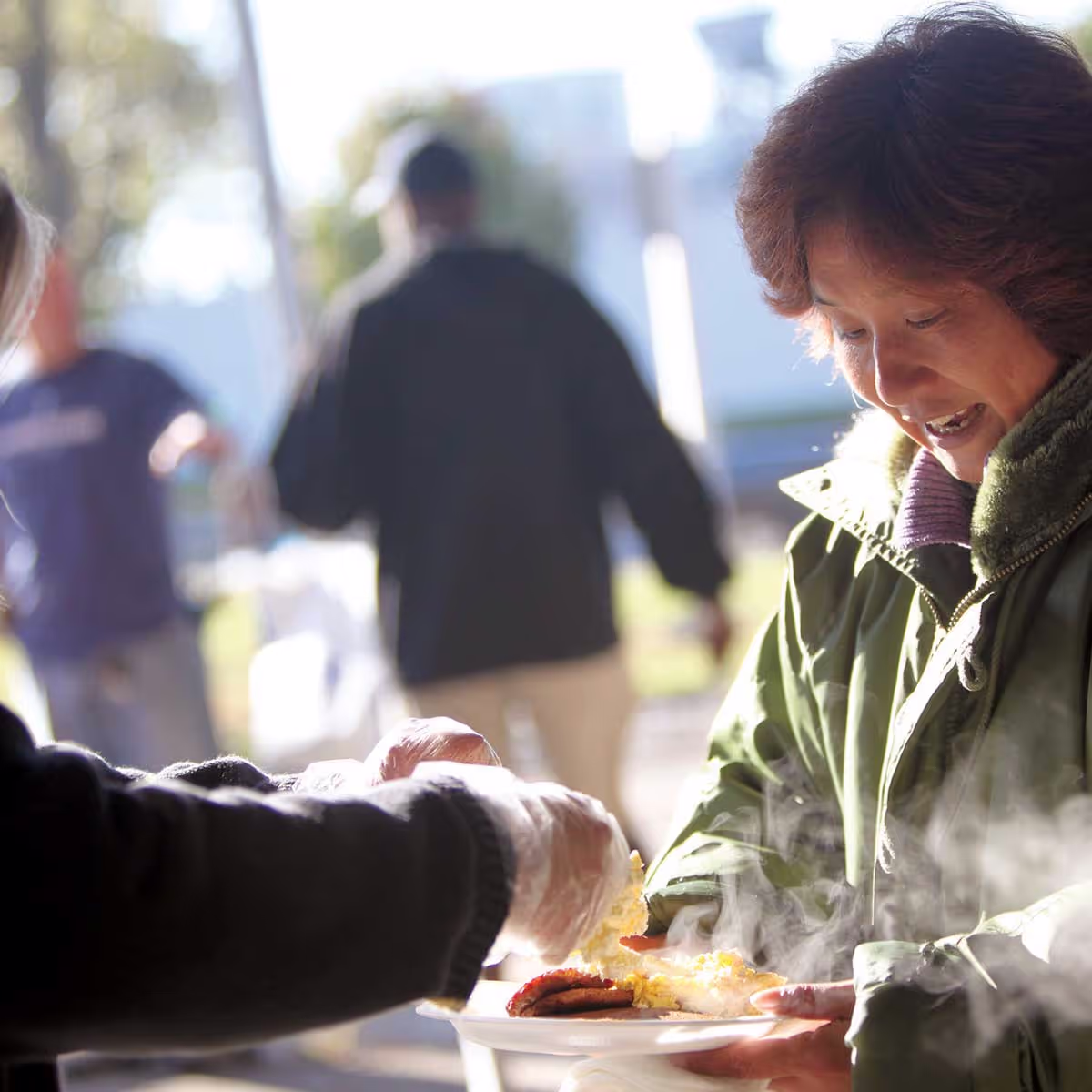 A woman being served food in an outdoor setting