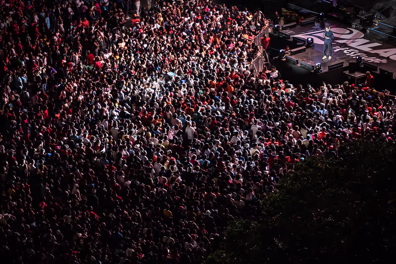 An aerial view of a large event with a man on stage speaking to the crowd