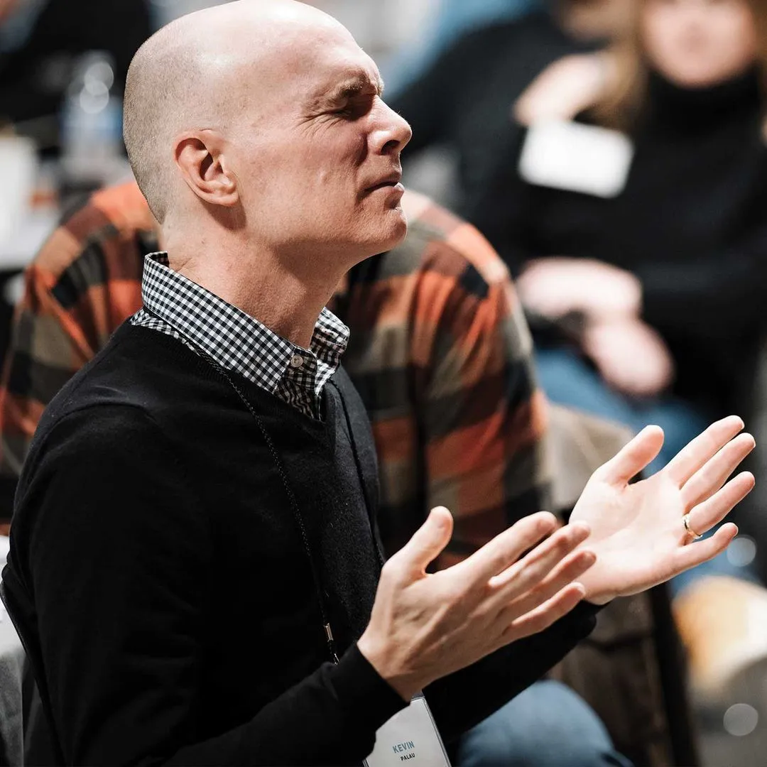 Kevin Palau with his eyes closed and his hands open in prayer