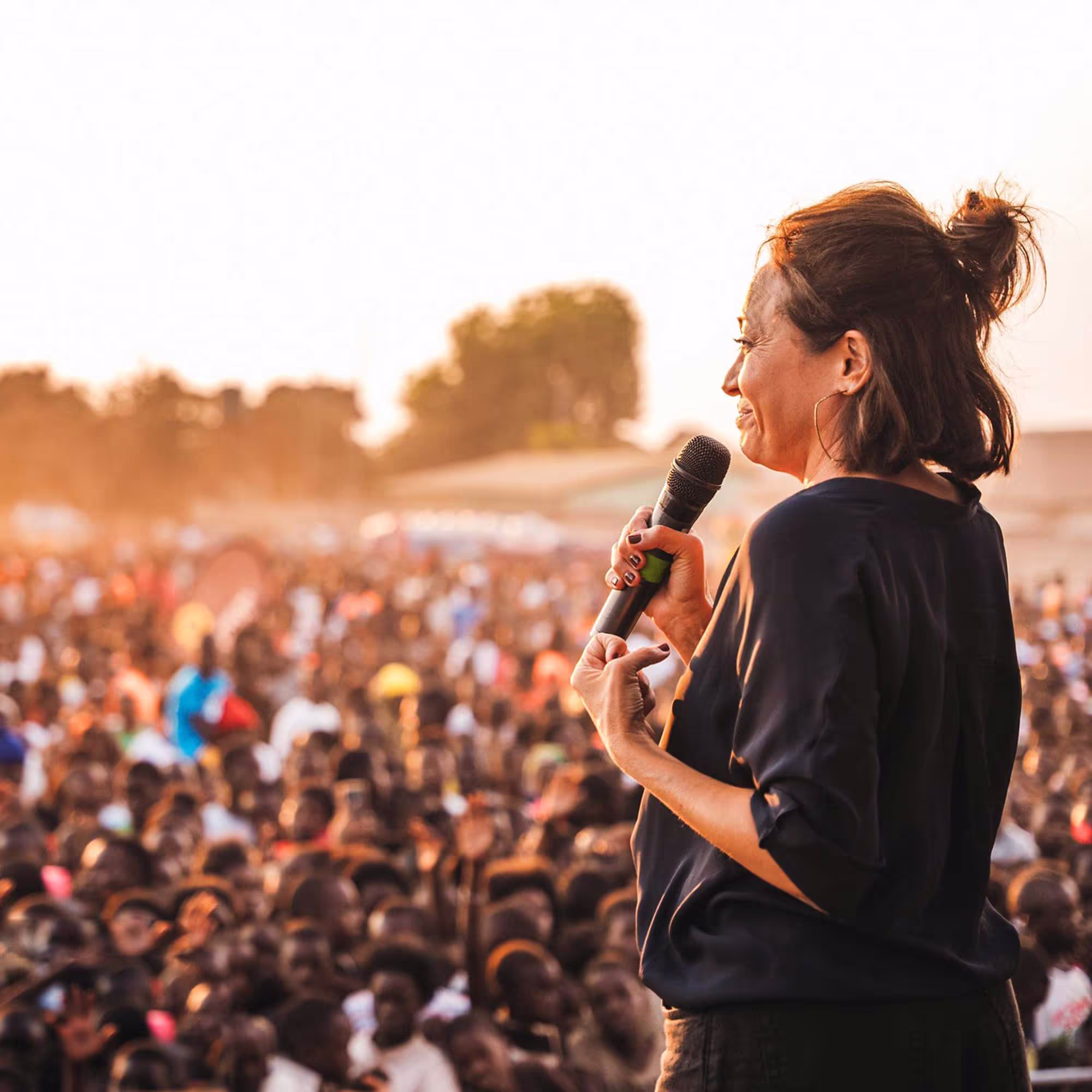 Wendy Palau on stage with a microphone standing in front of a large crowd of people 