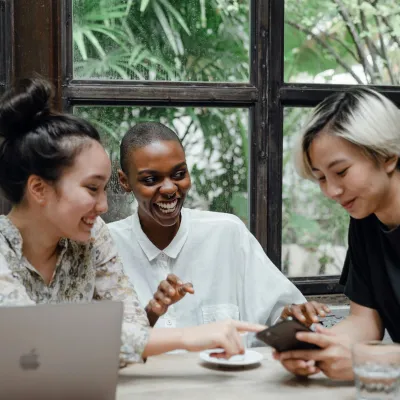 Group of students tracking study progress on a mobile app while working together in a cafe.