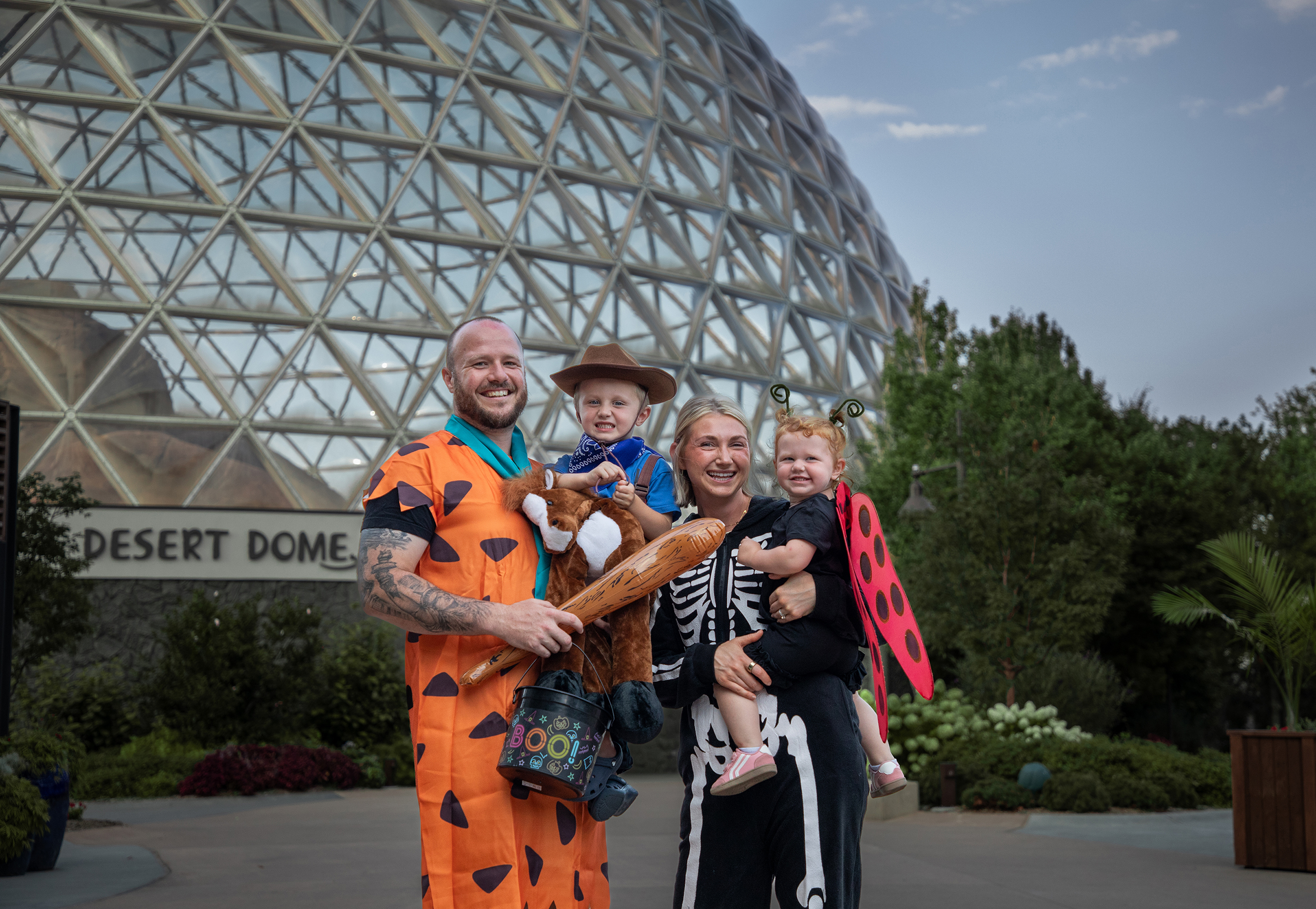 family with a mom and dad holding two children dressed up in Halloween costumes