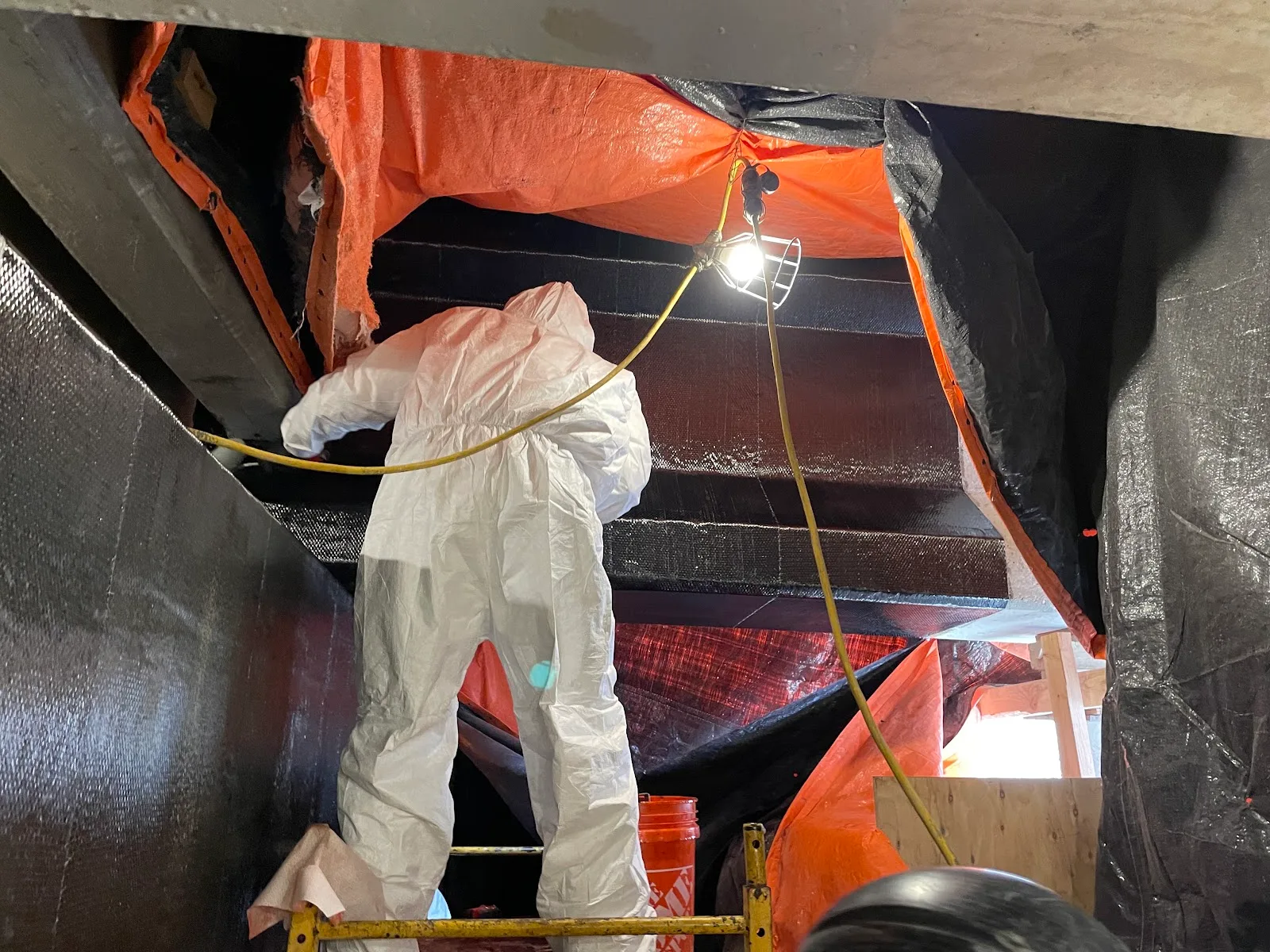During: a crew member in a protective suit applies carbon fiber fabric to repaired bridge beams.
