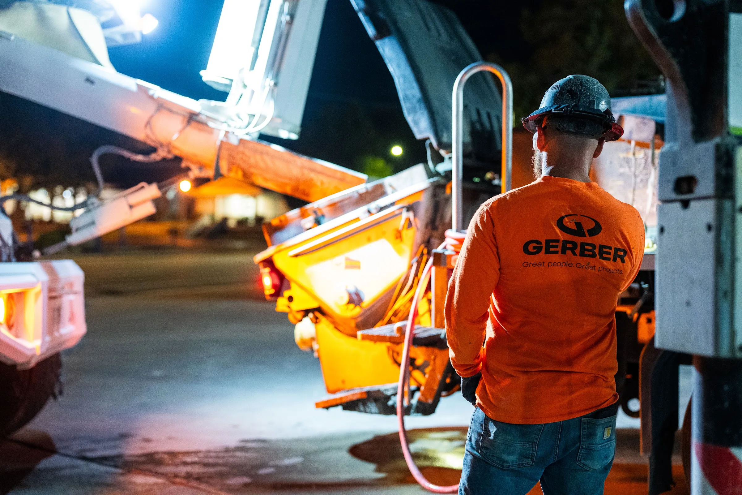 A concrete pump places concrete on a stadium concourse at night.