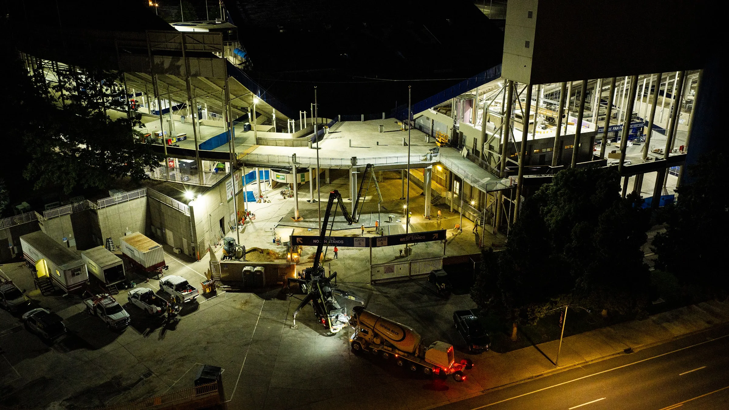 Crews place concrete on a stadium concourse at night, behind the scenes, so the venue is ready for the people who use it.