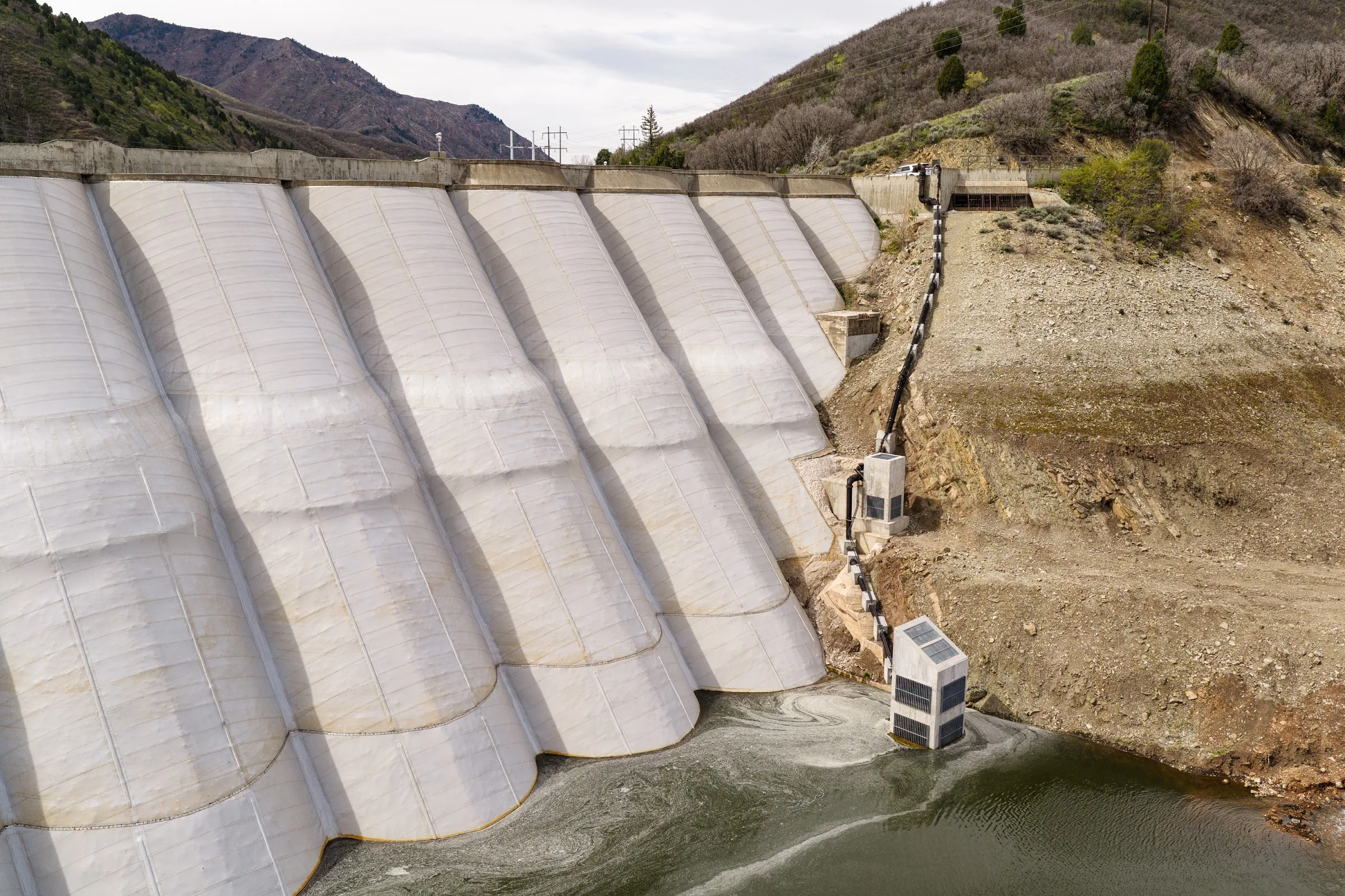 The restored concrete arches of a multi-arch dam above the water line.