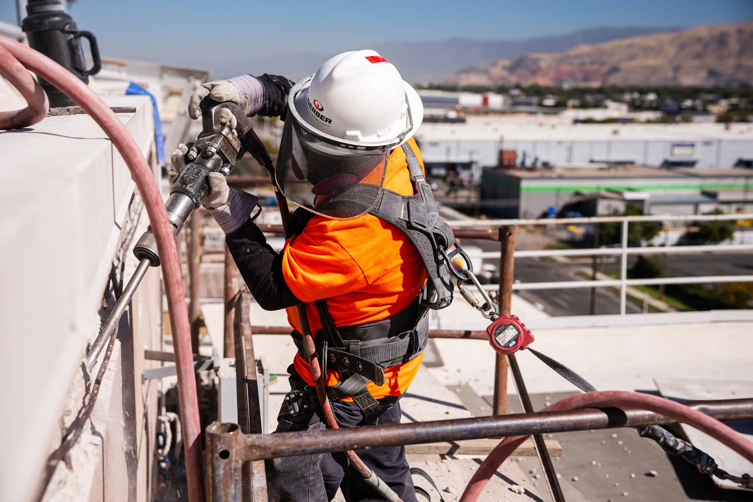 A harnessed Gerber crew member prepares the concrete surface at the top edge of a tower.