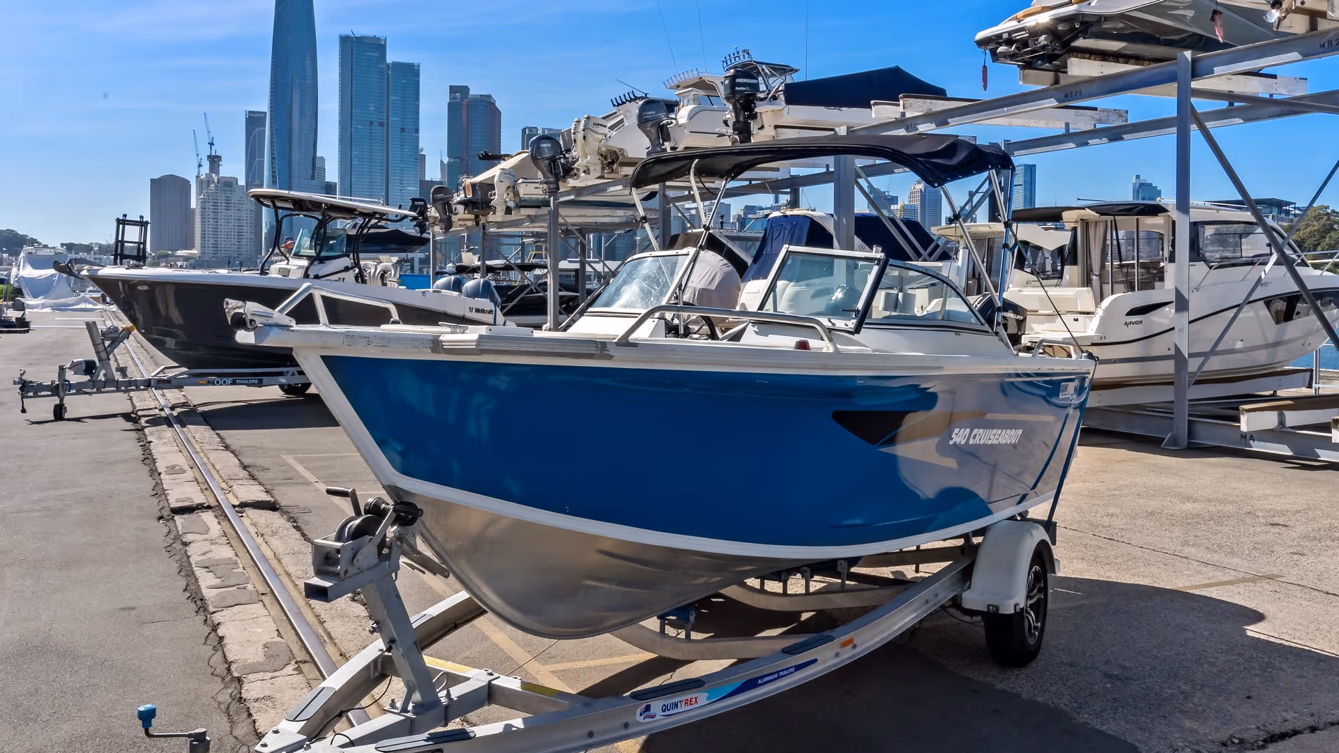 Line of sleek boats on a dock under a clear blue sky with city skyscrapers in the background, creating a vibrant, adventurous atmosphere.