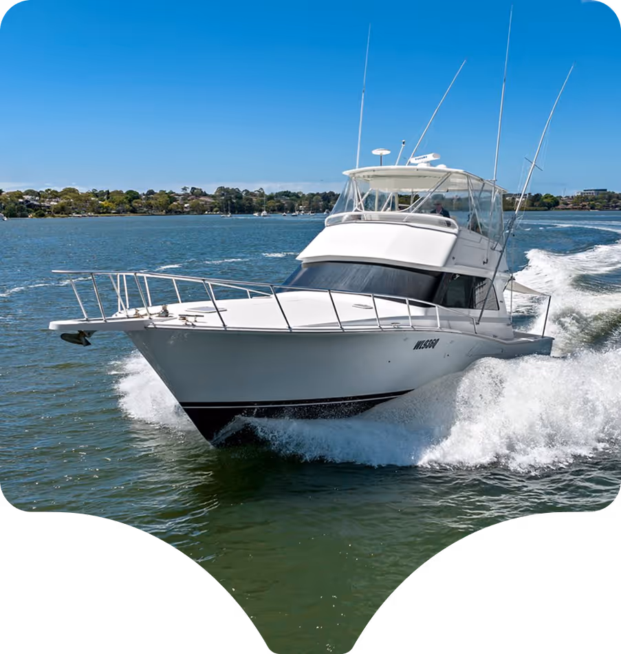 A white yacht speeds through a calm, blue sea, creating waves. The sky is clear and sunny. The scene conveys adventure and freedom.
