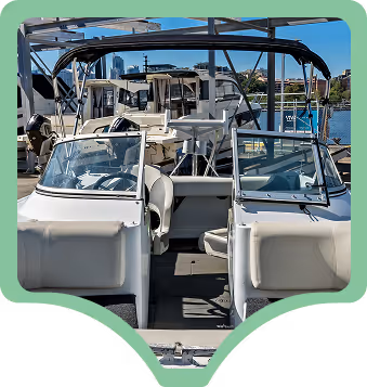 A row of white boats docked at a marina under a clear sky, featuring open seating areas and navigation equipment, with a city skyline in the background.