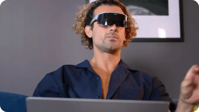 Person wearing Visor headset and working on a laptop, appearing to interact with a virtual interface.