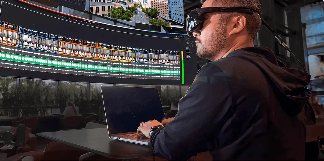 Person wearing Visor headset while editing video using multiple large floating virtual screens.