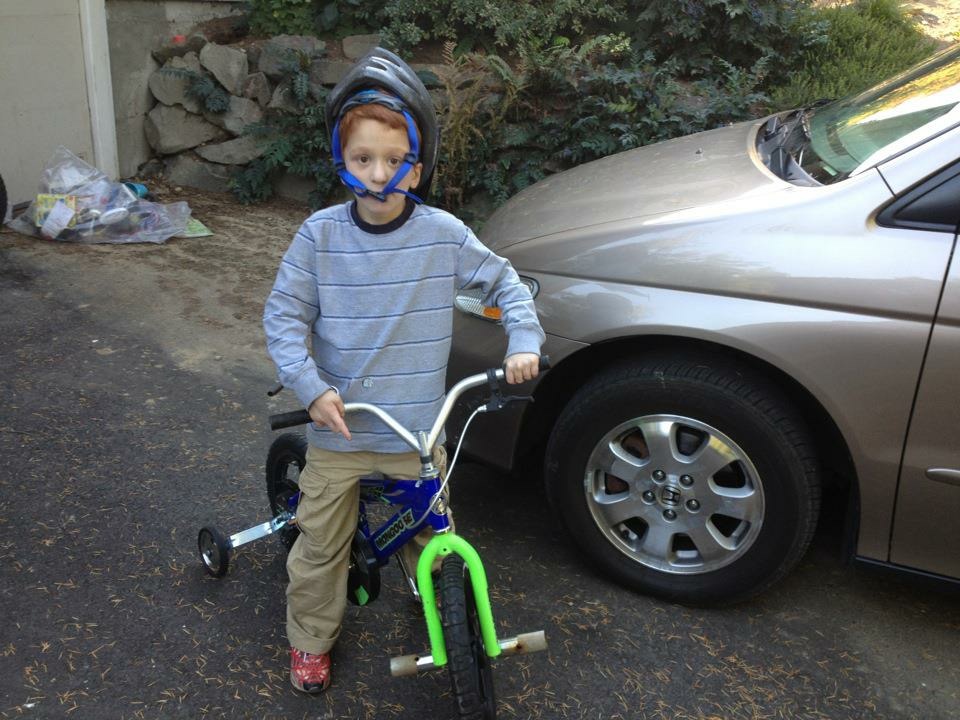 Nate on a bike, with helmet strap across his face.