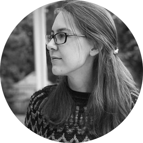 Black and white profile of a woman with glasses and long hair tied back wearing a patterned sweater.