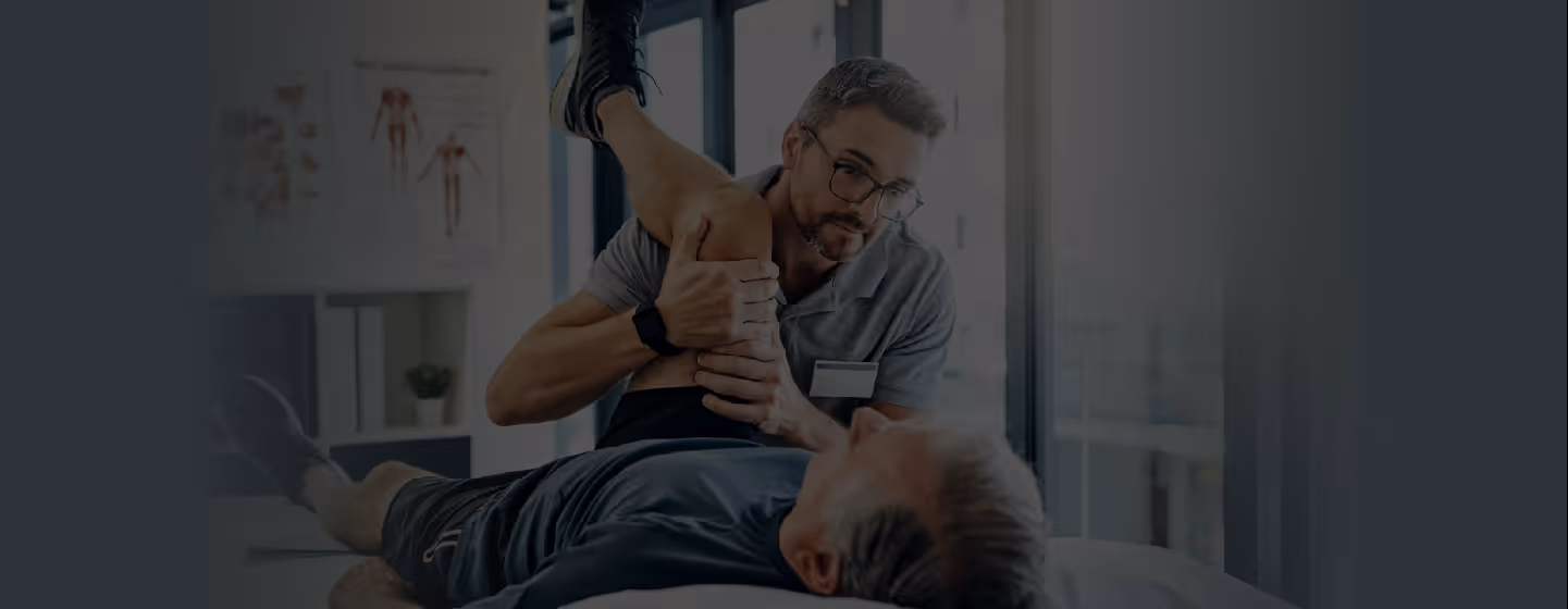 Physical therapist stretching a patient's leg in a medical clinic setting.