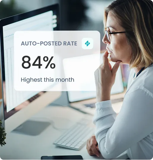 Woman with glasses looking at a computer screen showing 84% auto-posted rate, highest this month.