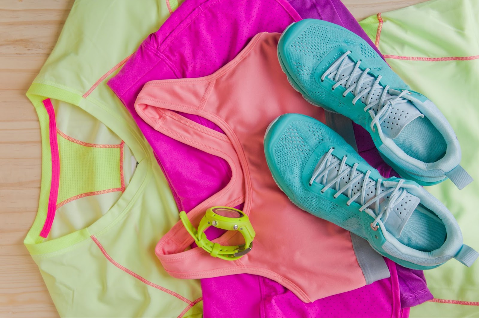 Colorful workout clothes and fitness gear on a wooden surface.