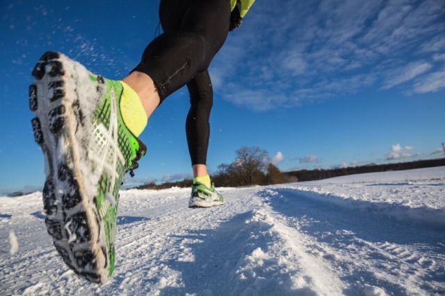 A person running swiftly across a snow-covered landscape, leaving footprints in the fresh snow.